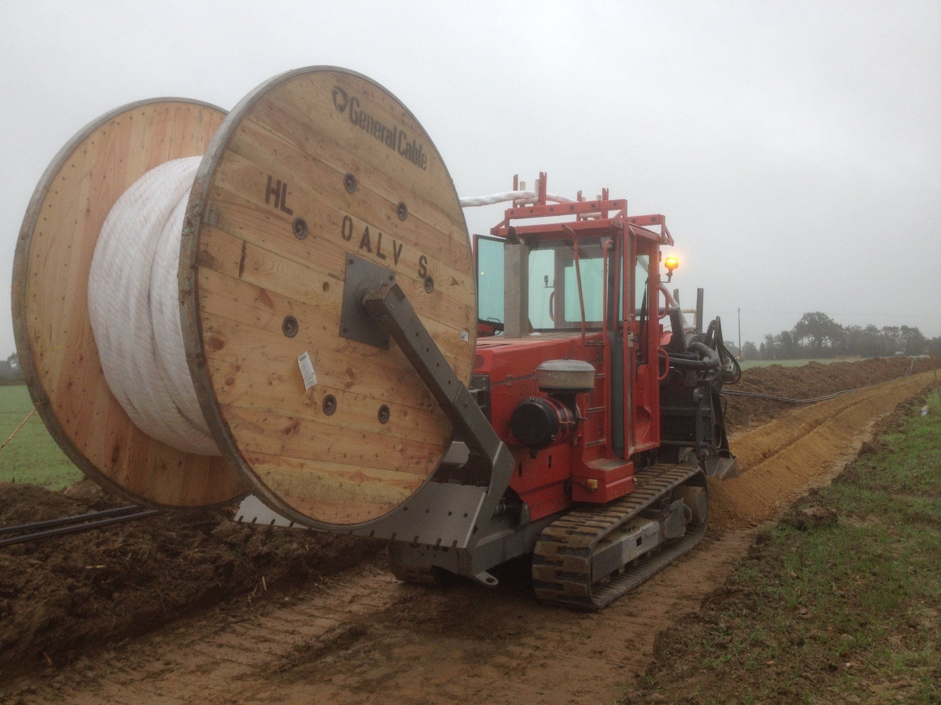 Machine rouge déroulant du câble dans un champ