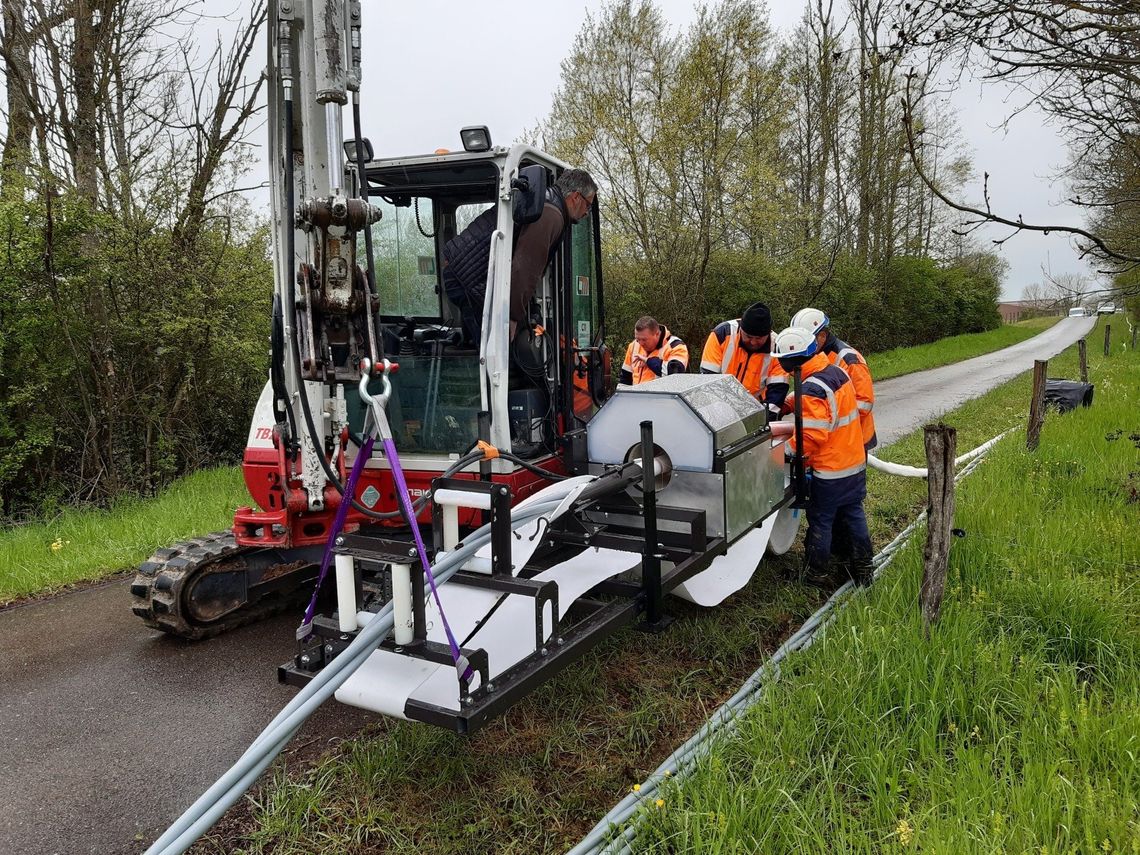 Machine de travaux publics blanche avec des ouvrirers au travail