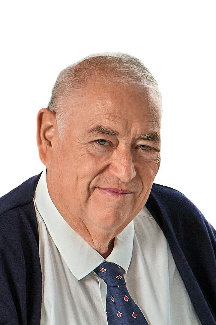 Ein Mann in weißem Hemd und Krawatte lächelt in die Kamera.