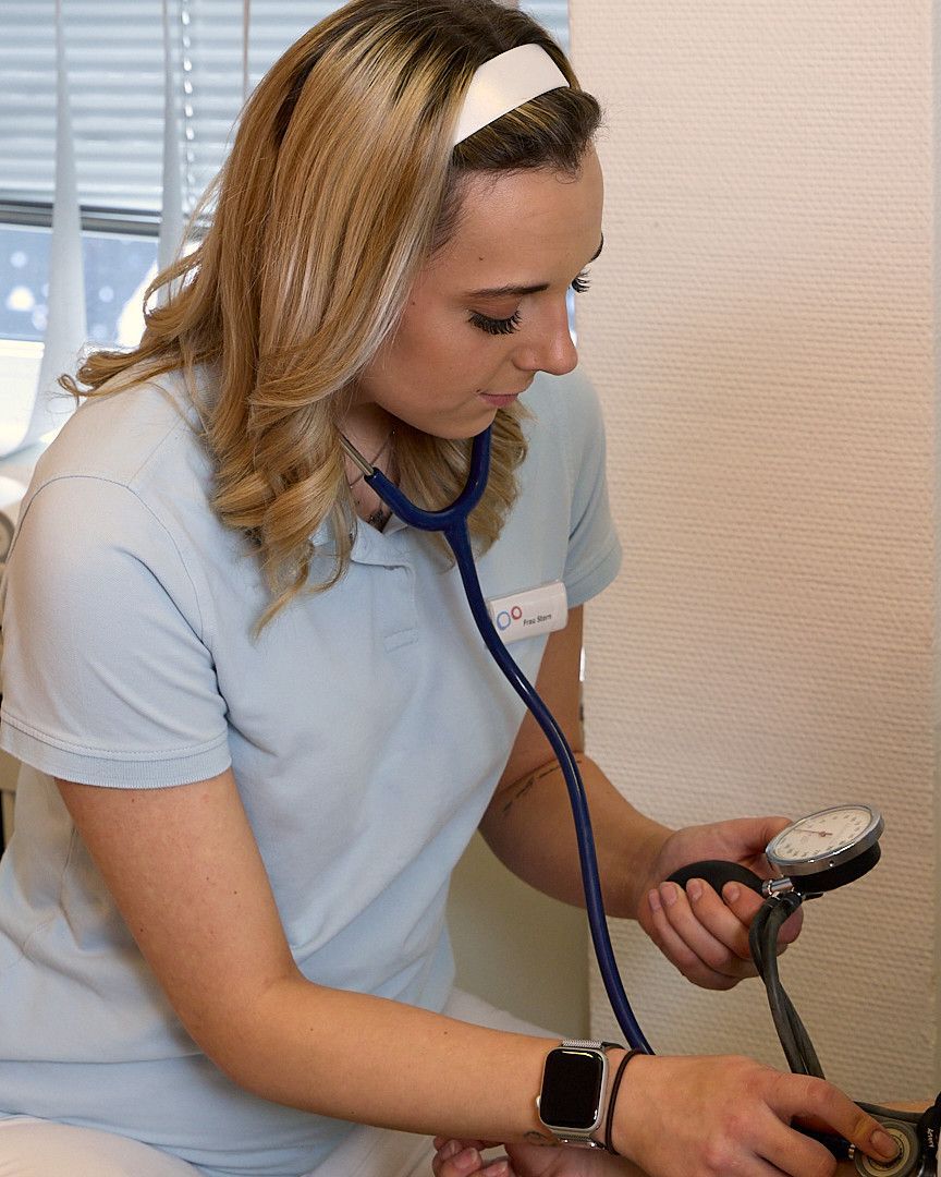 Eine Frau hört mit einem Stethoskop den Herzschlag eines Patienten ab