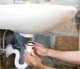 Una persona está arreglando una tuberÃa del lavabo de un baño.