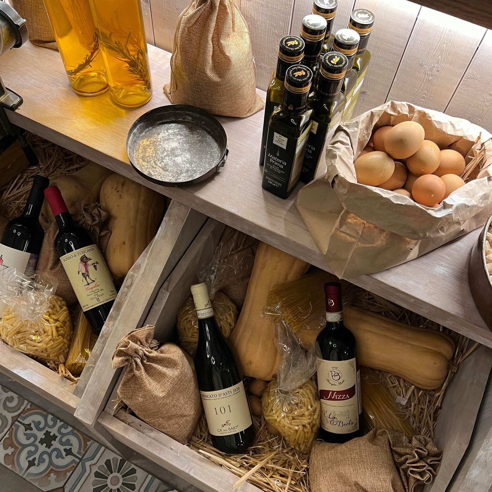 Un estante lleno de botellas de vino, huevos y pasta.