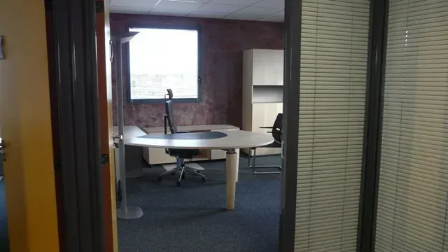 Salle de réunion vide avec table, chaises et stores.