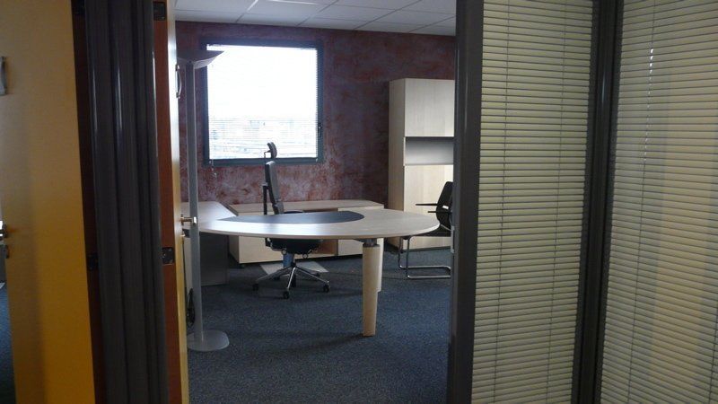 Salle de conférence avec table ronde, chaises de bureau et une fenêtre lumineuse en arrière-plan