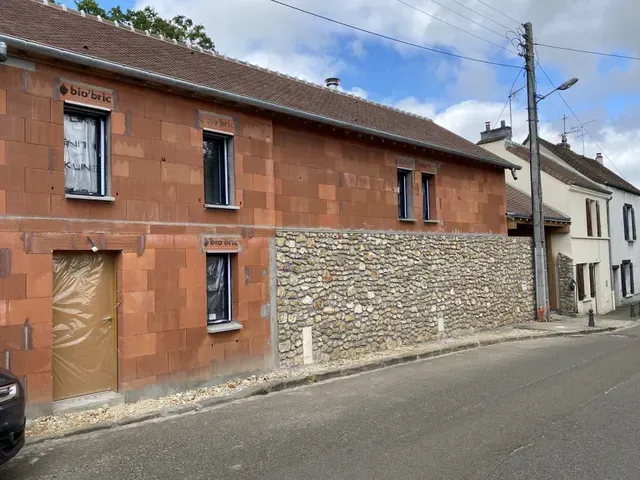 Maisons en briques et en pierres alignées le long d'une rue tranquille sous un ciel partiellement nuageux