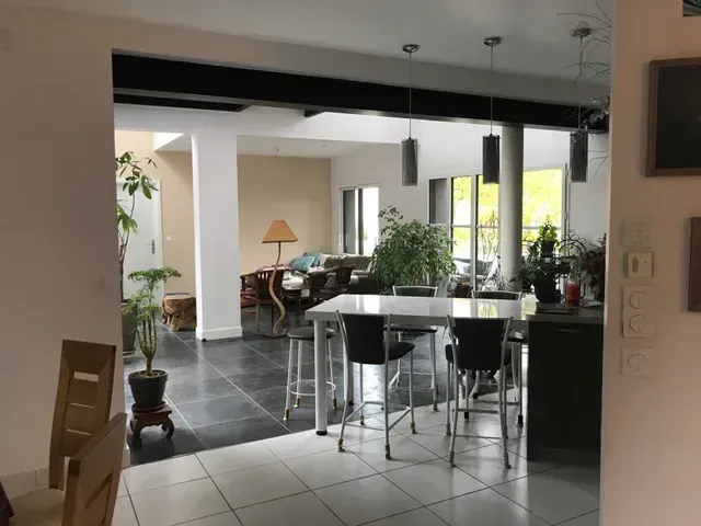 Salle à manger moderne à aire ouverte avec sol carrelé noir, murs blancs et grandes fenêtres.