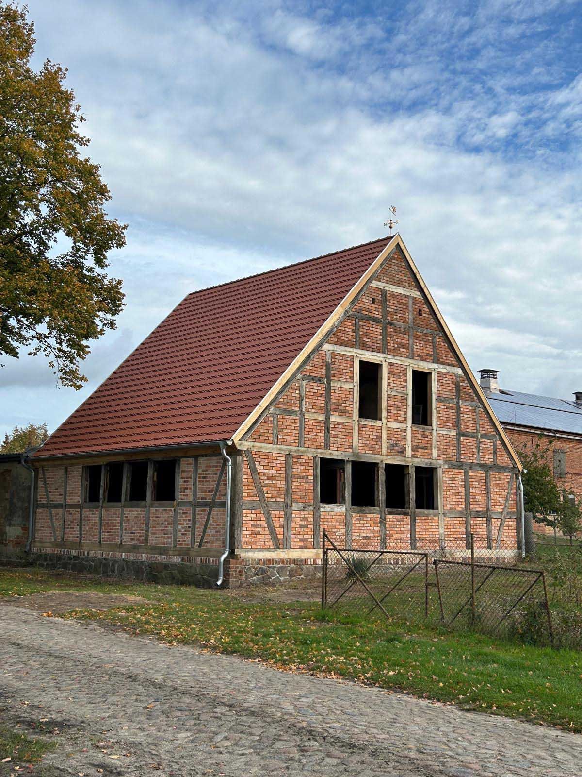Umbau und Sanierung eines Backsteinhauses mit rotem Dach.