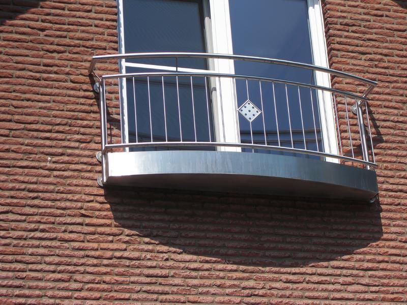 ein Backsteingebäude mit einem Balkon mit Edelstahlgeländer