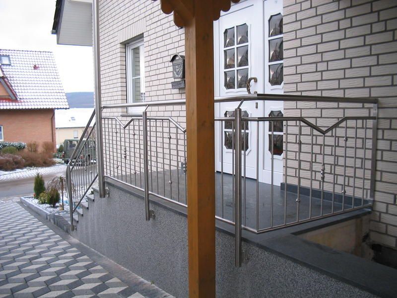 ein weißes Backsteinhaus mit einem Geländer aus Edelstahl