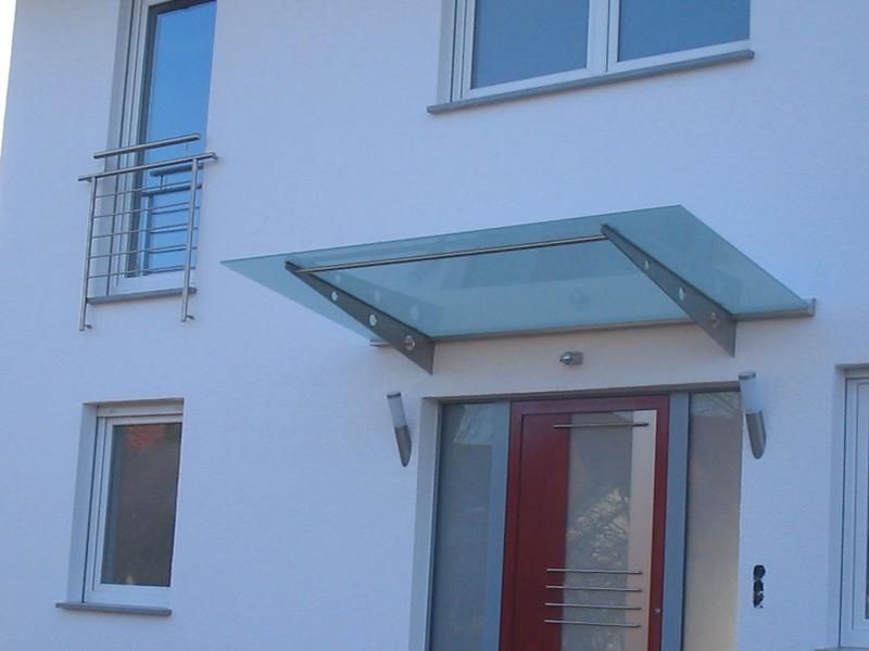 ein weißes Haus mit einer roten Tür und einem Glasdach