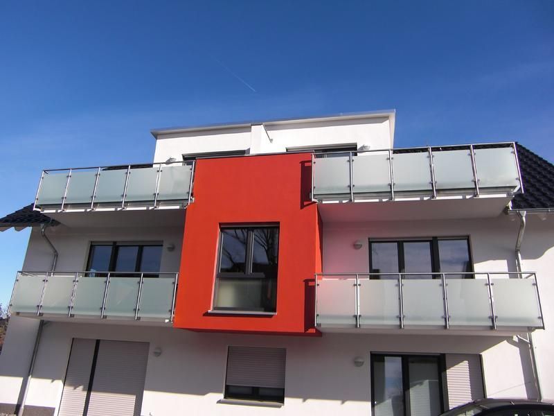 ein weißes Gebäude mit einer roten Ecke und Balkonen