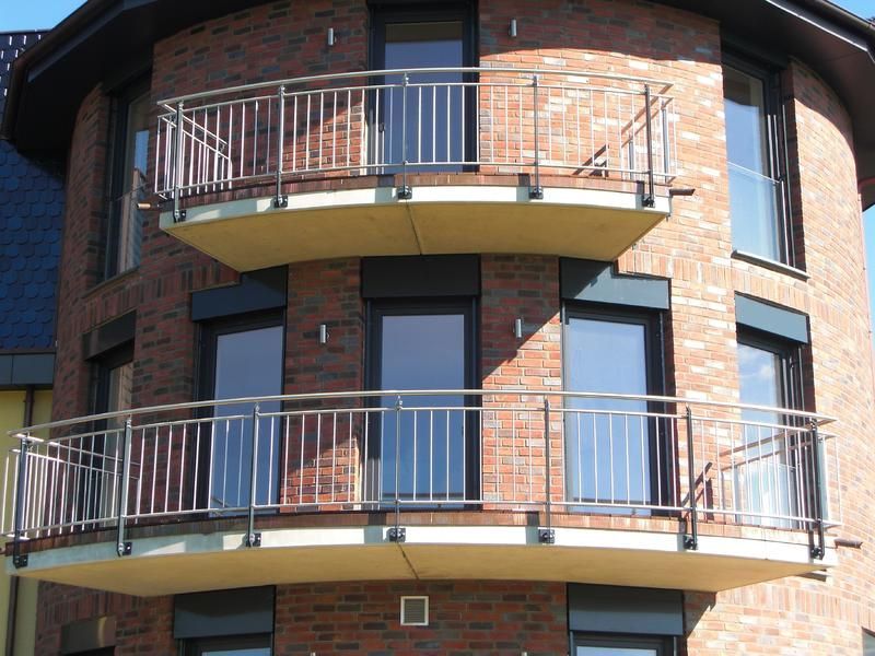 ein Backsteingebäude mit drei Balkonen und einem Geländer aus Edelstahl