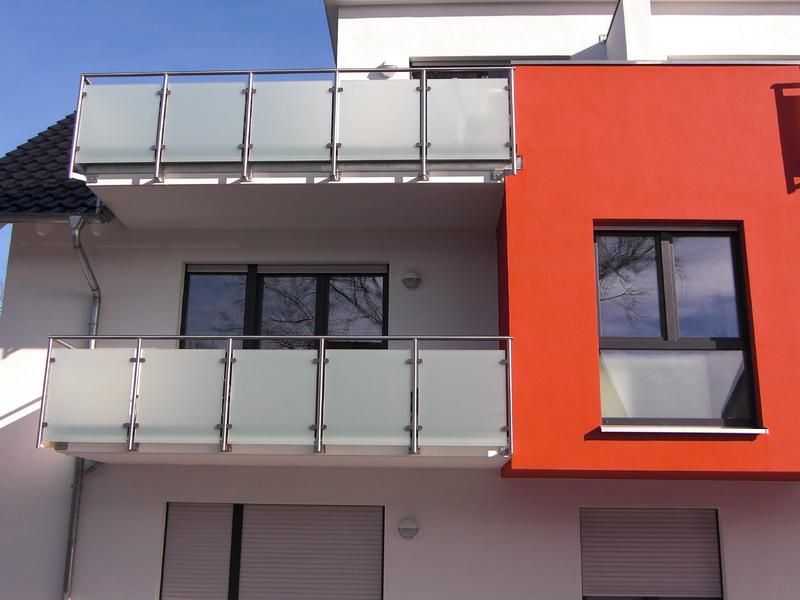 ein weiß-orangefarbenes Gebäude mit Balkon