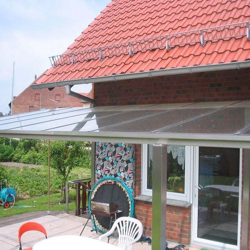 Ein Haus mit rotem Dach verfügt über eine Terrasse mit Tisch und Stühlen