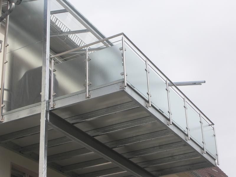 ein Balkon mit einem Glasgeländer an der Seite eines Gebäudes