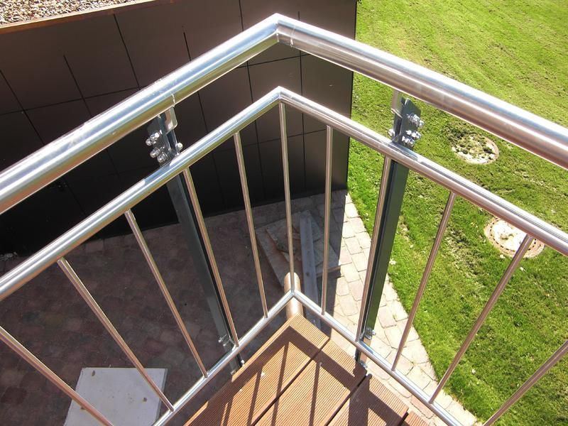 ein Edelstahlgeländer auf einem Balkon mit Blick auf eine üppige grüne Wiese