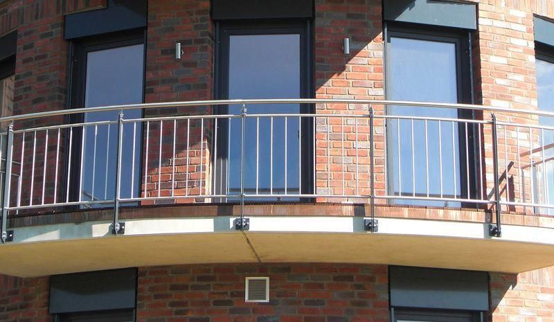 ein Balkon mit einem Edelstahlgeländer auf einem Backsteingebäude