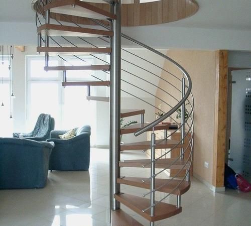 eine Wendeltreppe in einem Wohnzimmer mit blauen Stühlen