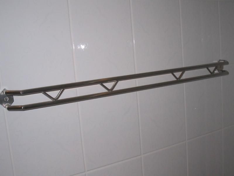 An einer weiß gefliesten Wand hängt ein Handtuchhalter