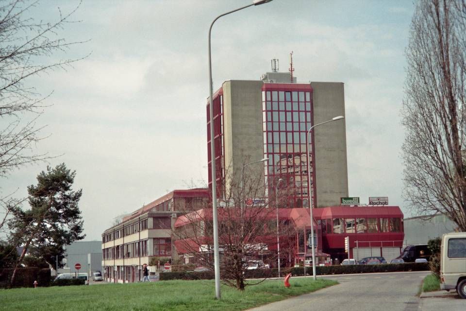 Un grand bâtiment avec beaucoup de fenêtres se trouve sur le bord d'une route.