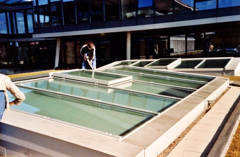 Un homme se tient devant un bâtiment avec une mare d'eau.
