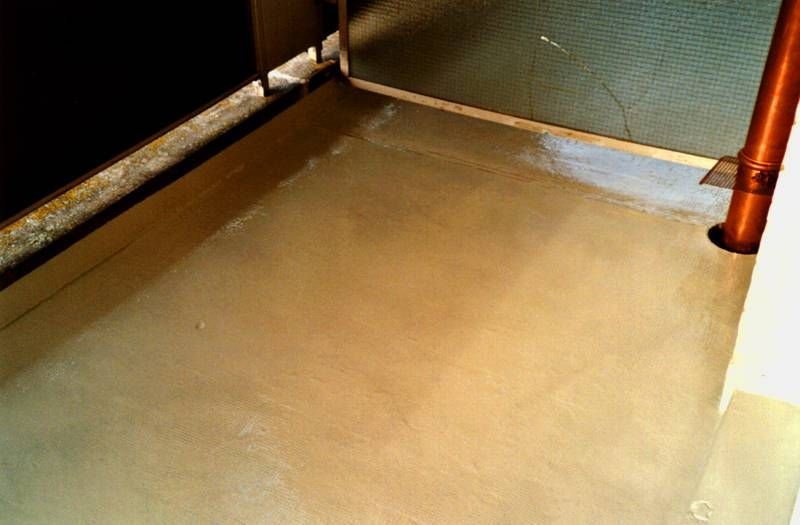 Un gros plan d'un sol en béton avec un tuyau en cuivre en arrière-plan.