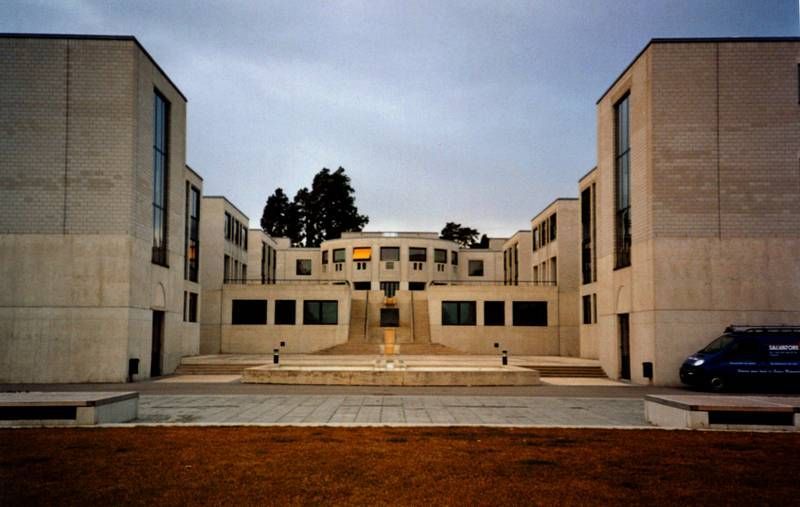 Un grand bâtiment avec une camionnette bleue garée devant