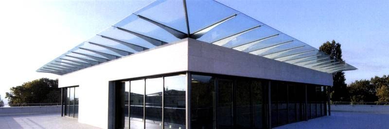 Un bâtiment blanc avec un toit en verre et beaucoup de fenêtres.