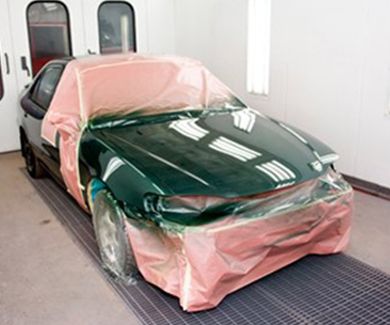 Se está pintando un coche verde en una cabina de pintura.
