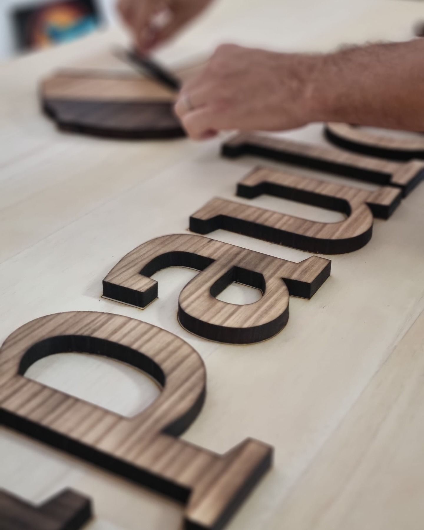 Persona quemando letras de madera sobre una superficie de madera clara.
