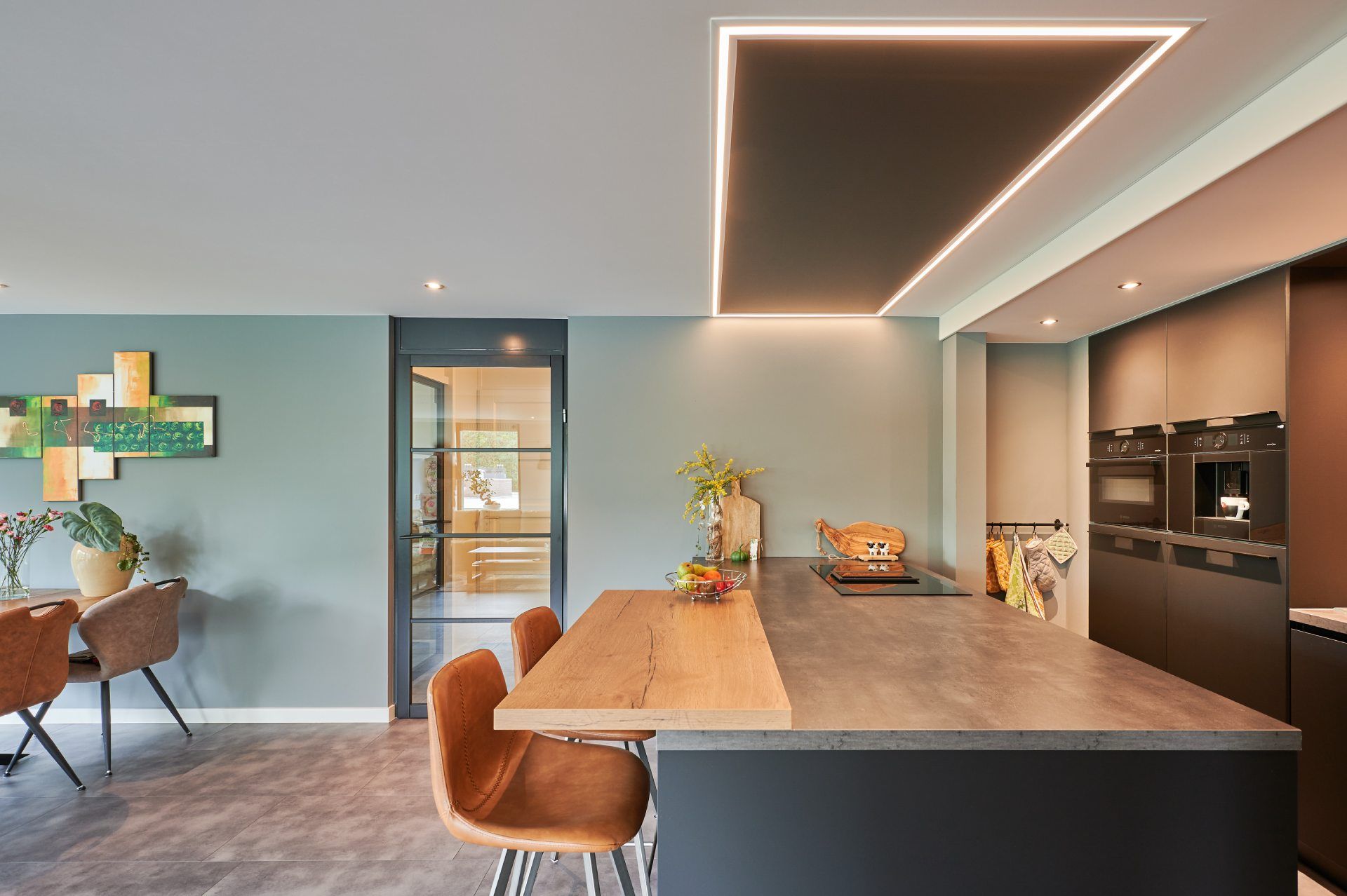 Kleine, offene und moderne Küche mit Setzgelegenheiten und einer flachen Deckenleuchte