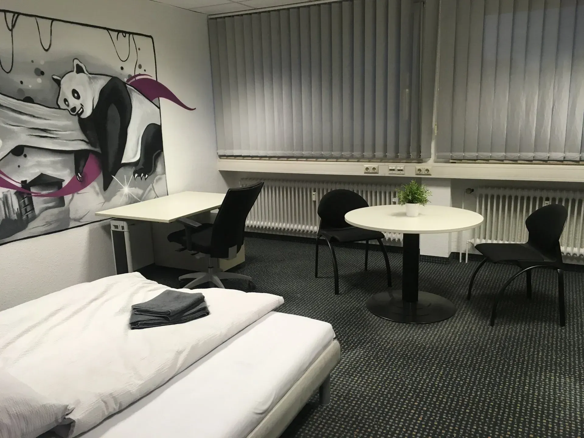 Ein Schlafzimmer mit einem Panda-Gemälde an der Wand