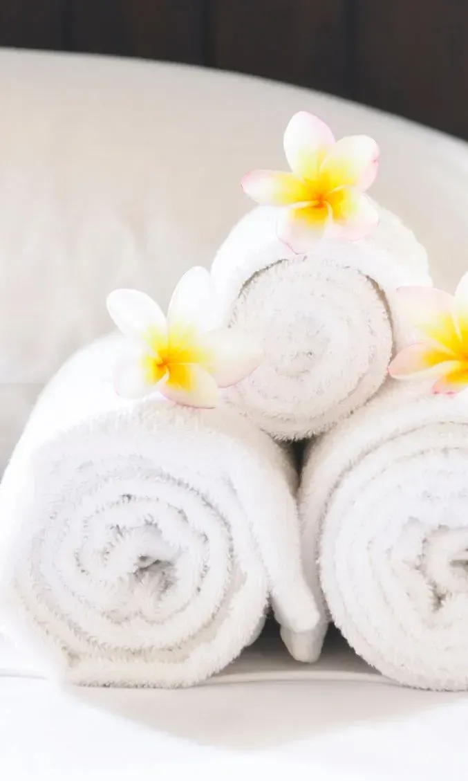 Ein Stapel weißer Handtücher mit Blumen darauf.