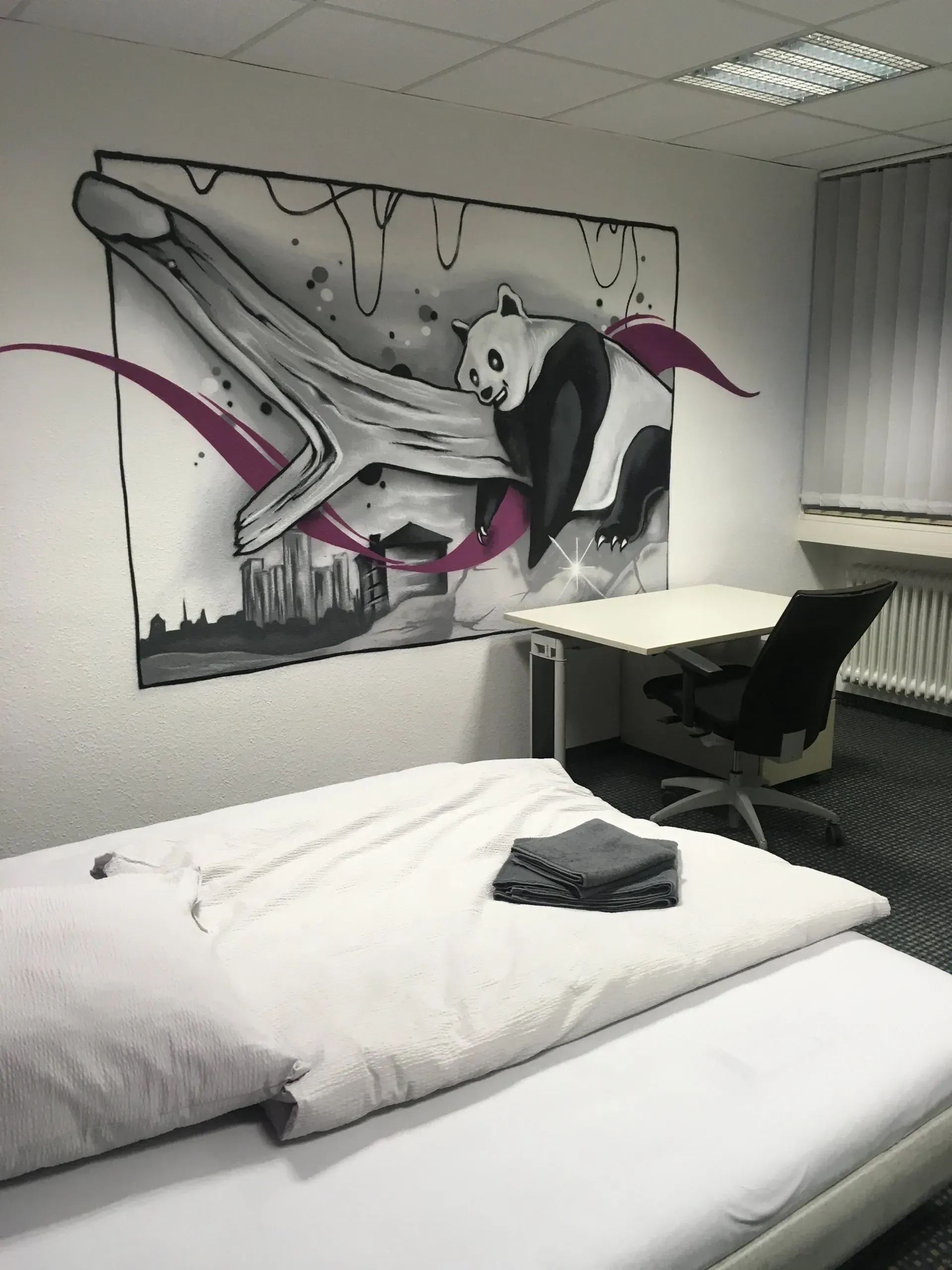 Ein Schlafzimmer mit einem Panda-Gemälde an der Wand