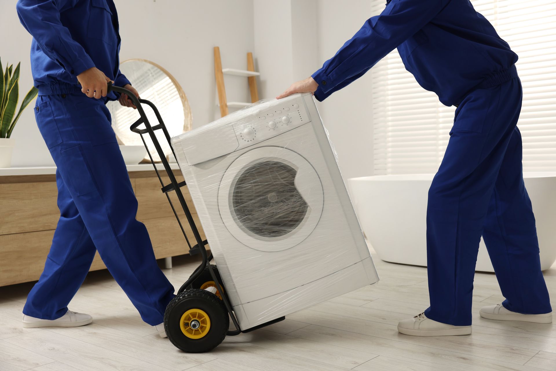 Des déménageurs déplacent un lave-linge avec un diable