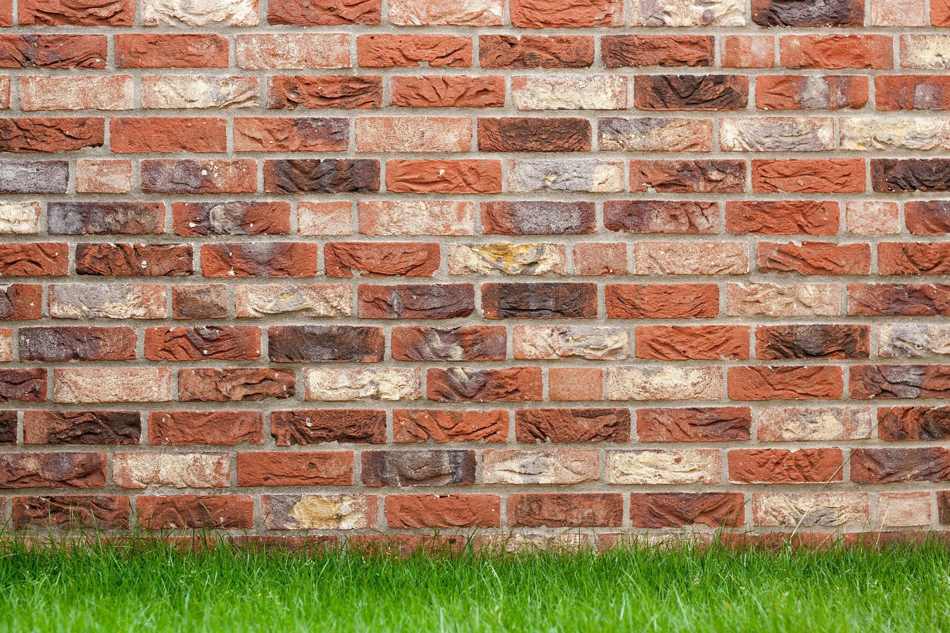 Una pared de ladrillos con césped delante.
