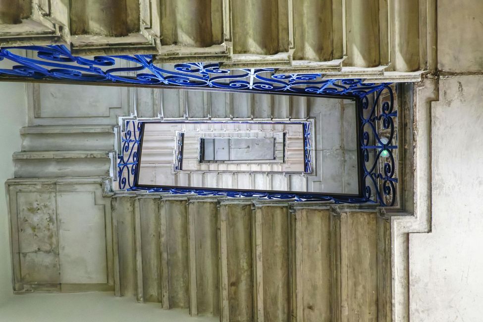 Mirando hacia arriba a una escalera con barandilla azul.