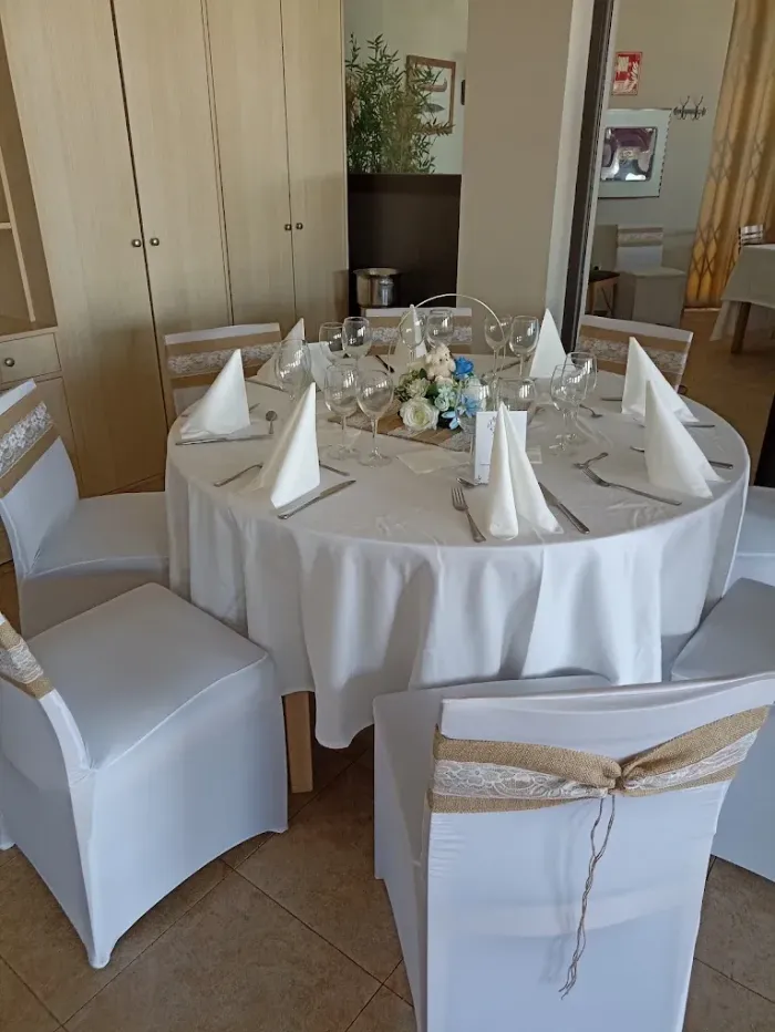 Mesa redonda para banquetes con manteles blancos y servilletas dobladas en un comedor decorado.