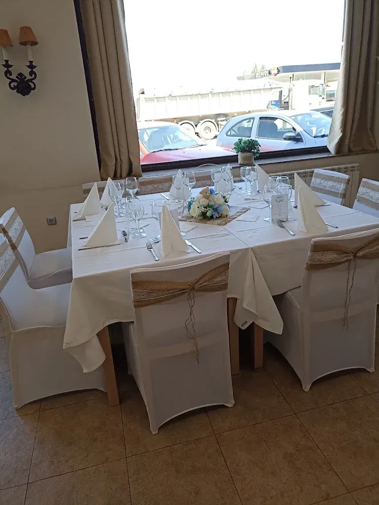 Mesa de comedor de restaurante preparada para una comida, con fundas blancas para las sillas