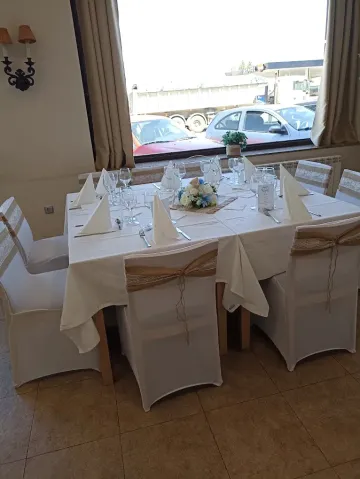 Mesa de comedor de restaurante preparada para una comida, con fundas blancas para las sillas