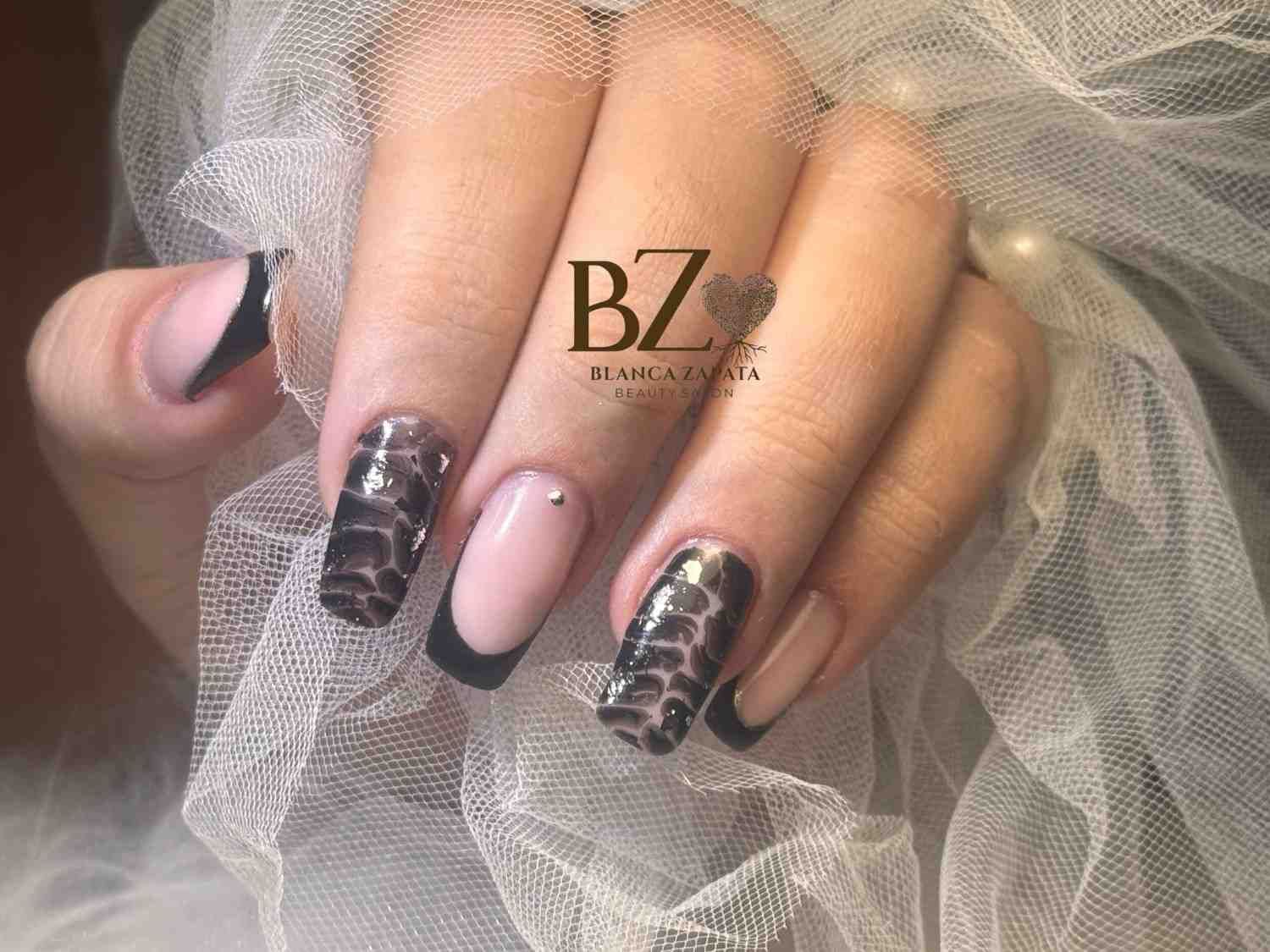 Primer plano de uñas manicuradas con decoración en negro y rosa sobre tul blanco transparente.