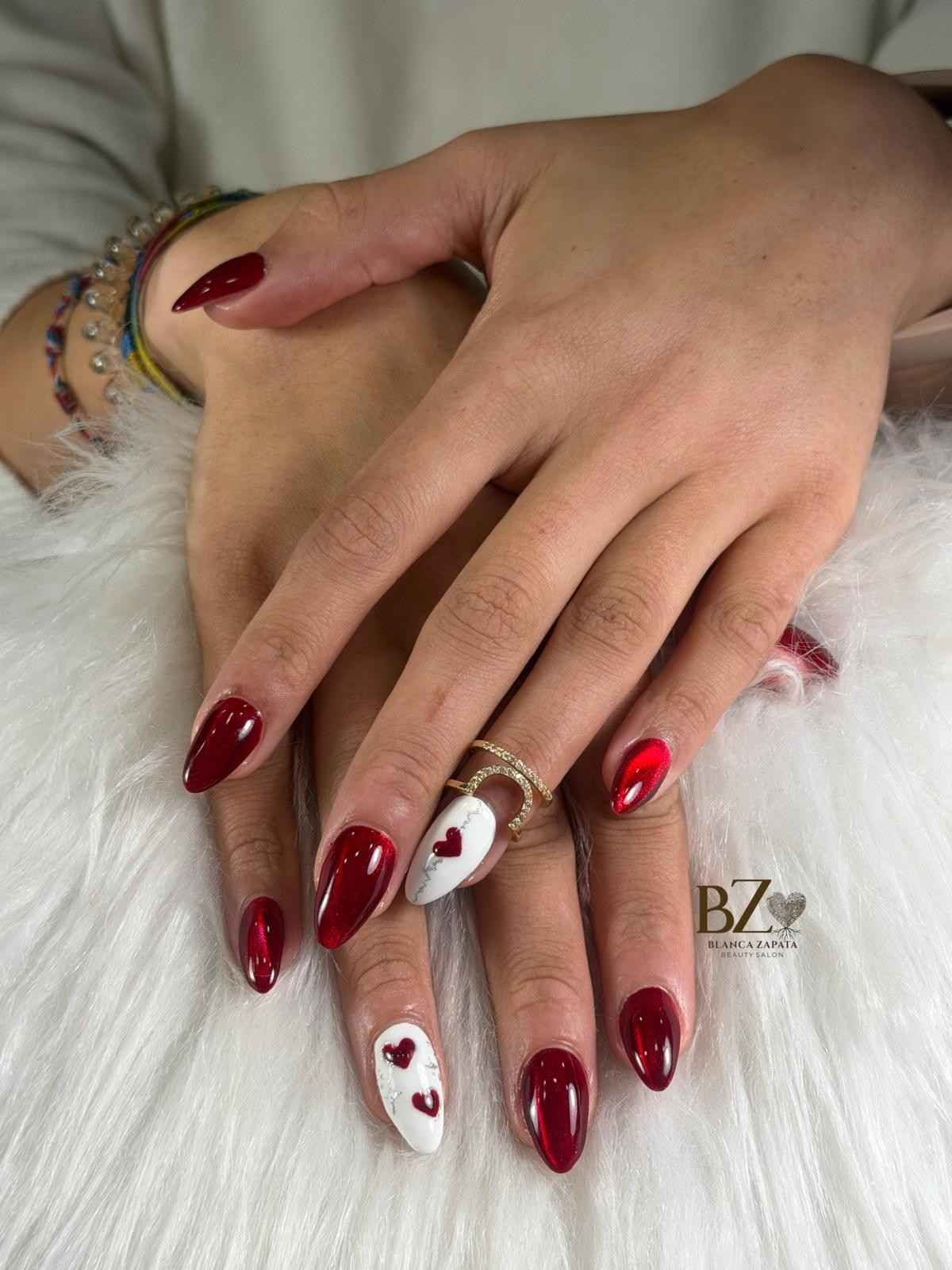 Manos con uñas decoradas en tonos burdeos y blanco, descansando sobre una superficie blanca y suave.