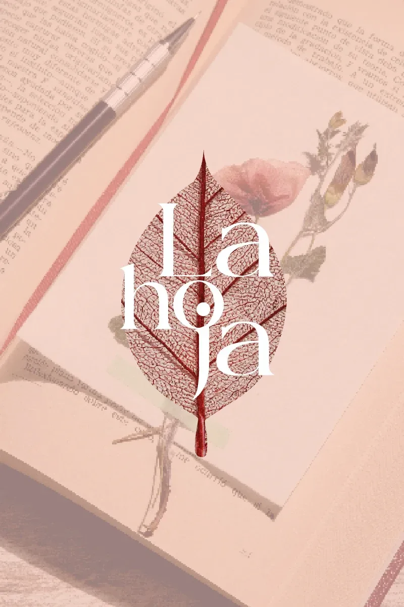 Cuaderno abierto con una ilustración de una hoja y un bolígrafo sobre un escritorio rosa.