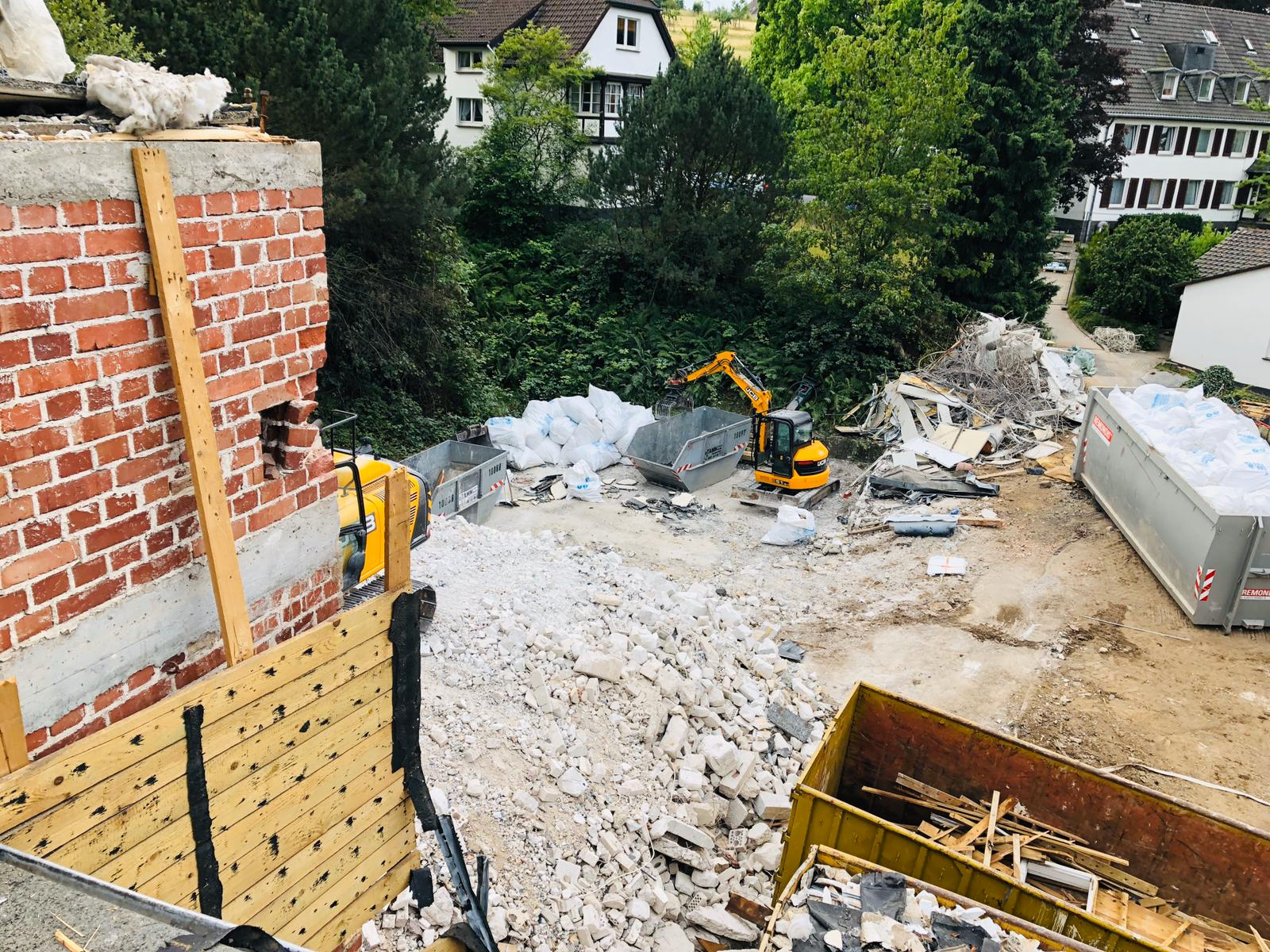 Abbruch arbeiten, Bagger schippt restlich Schutt in eine Absetzmulde.