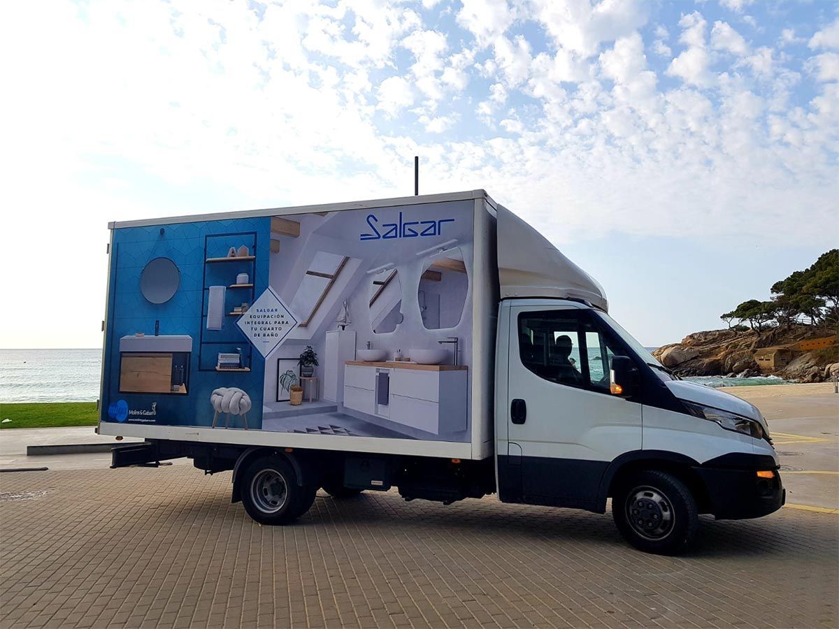 Camión de reparto blanco con un gran anuncio de cocina estacionado en la playa.