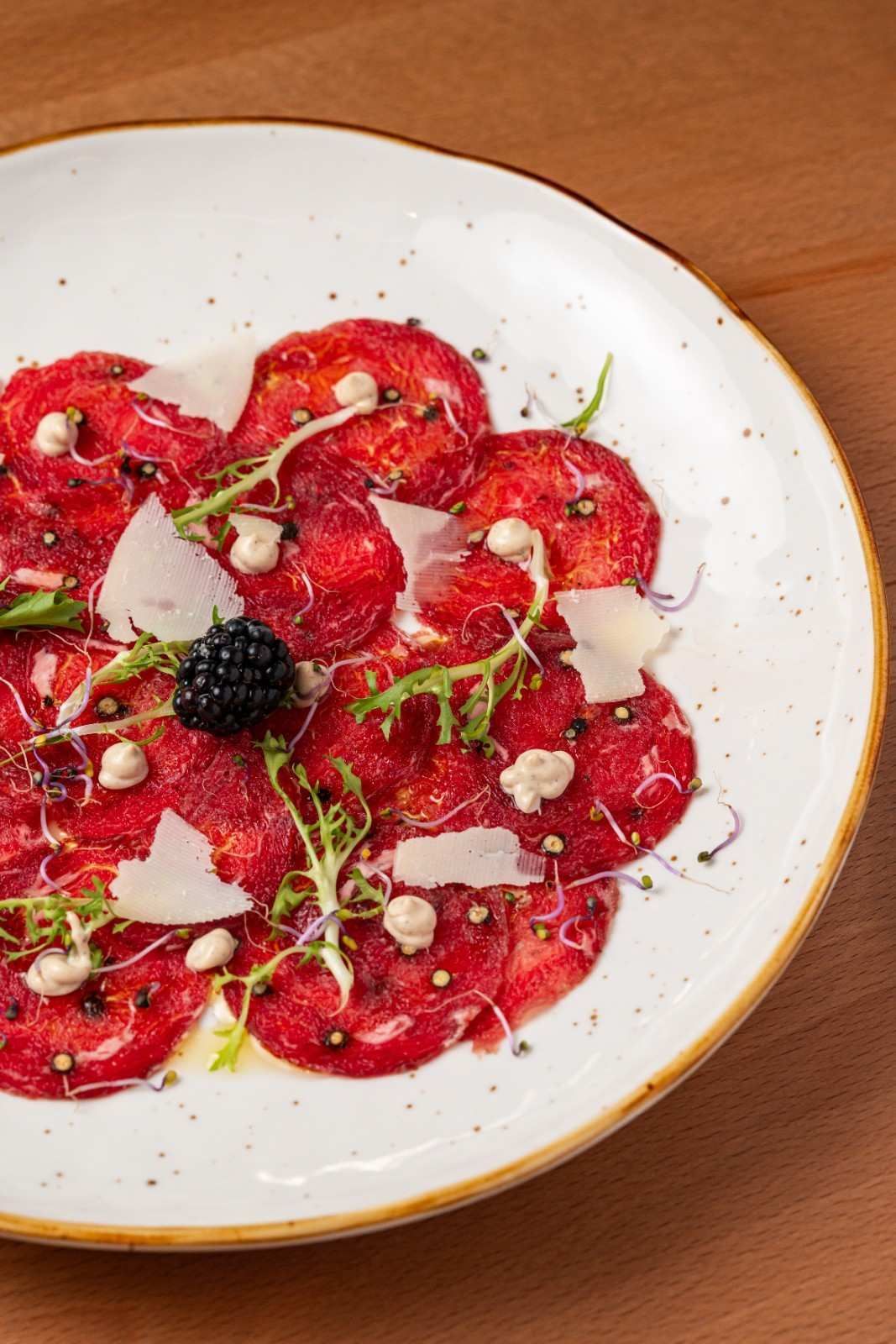 Ensalada de frutos rojos en rodajas con bayas, hierbas y coco en un plato blanco.