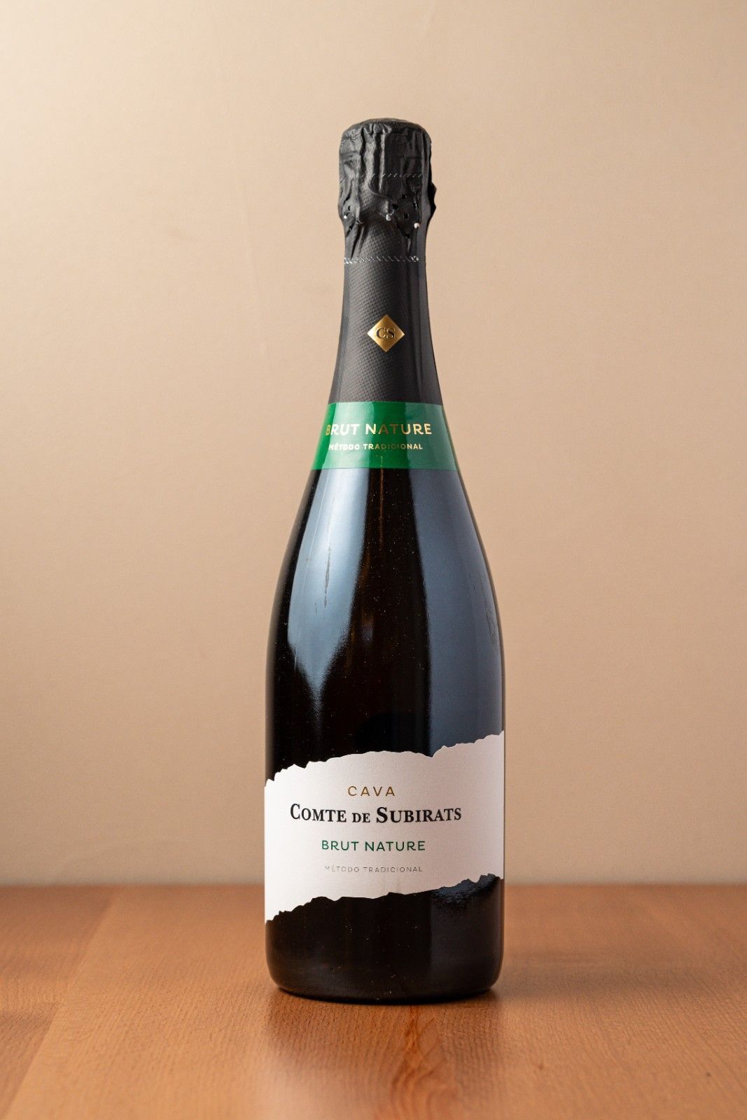 Una botella de champán colocada en posición vertical sobre una mesa de madera con un fondo beige.