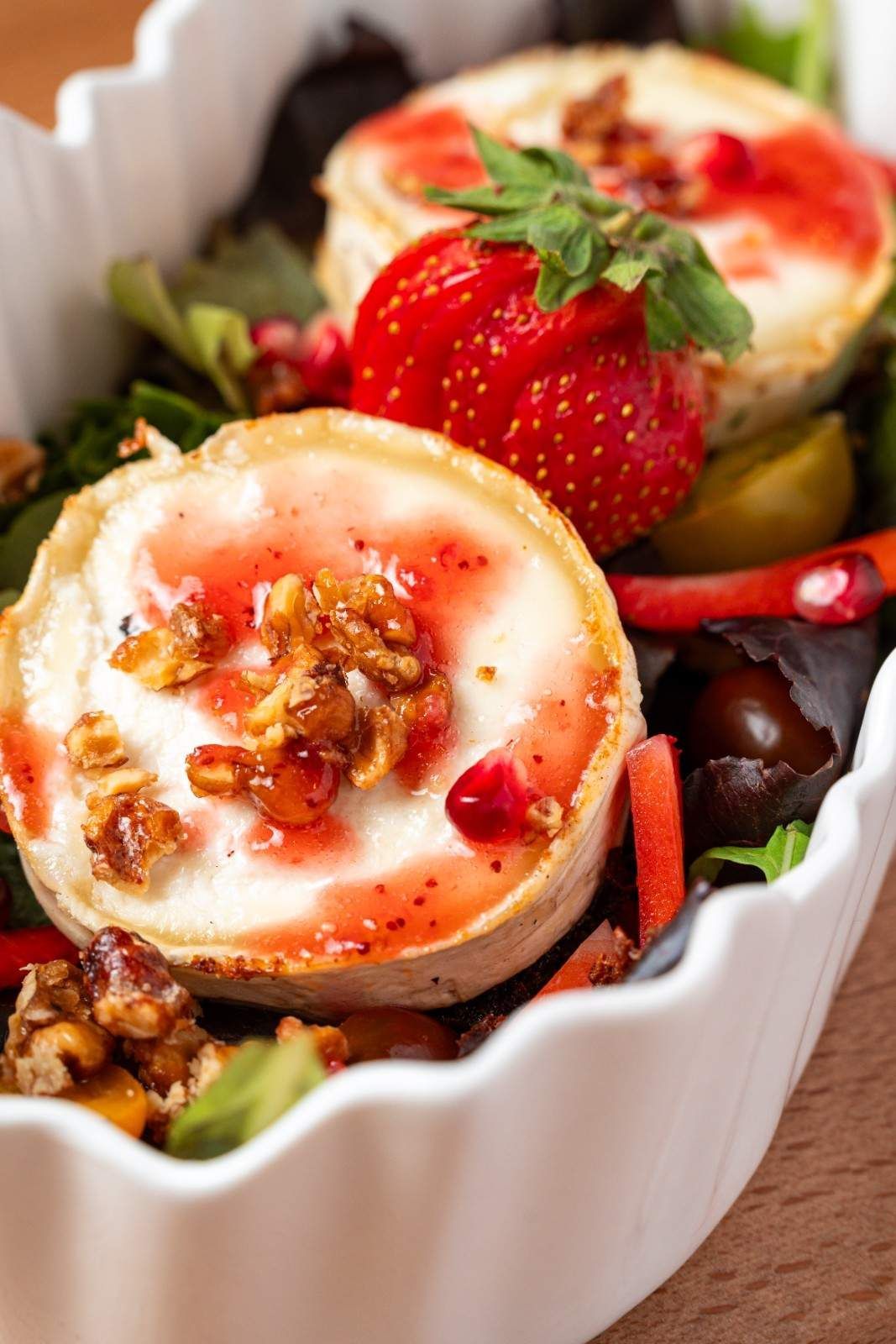 Bol de postre con yogur, fresas, granola y menta en un plato blanco.