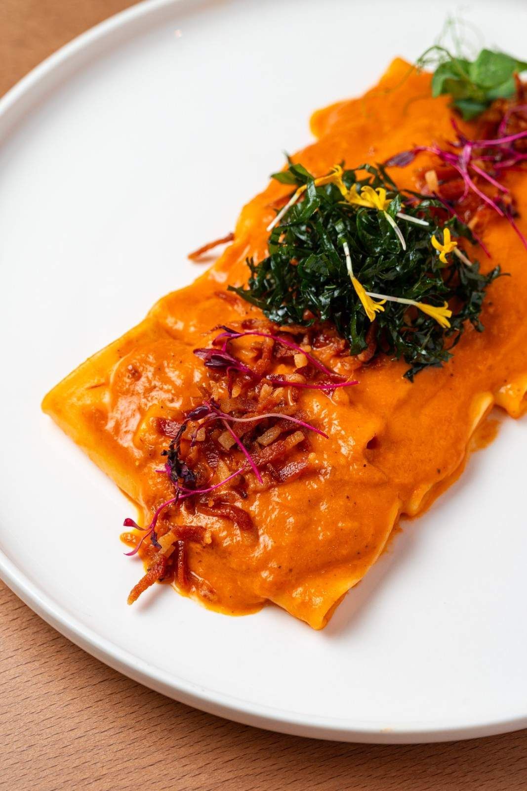 Salmón con salsa de naranja, cubierto con verduras y guarnición morada en un plato blanco.