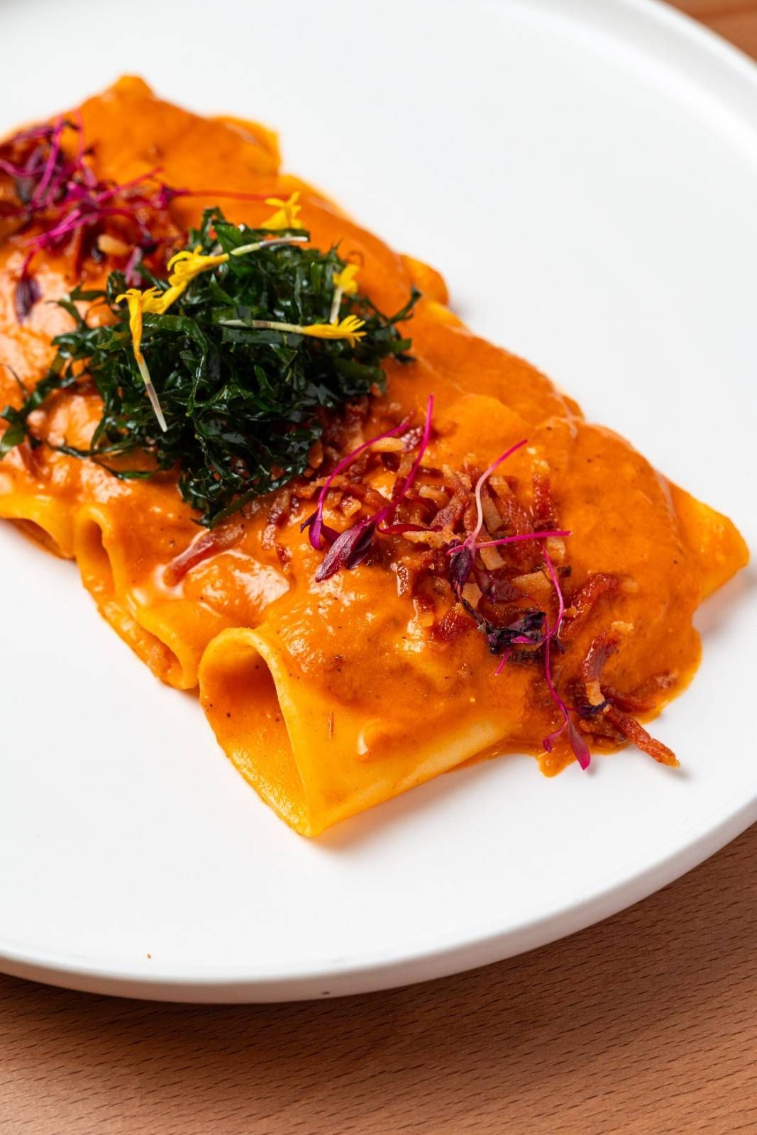 Pasta rellena de naranja con salsa de tomate y hierbas en un plato blanco.
